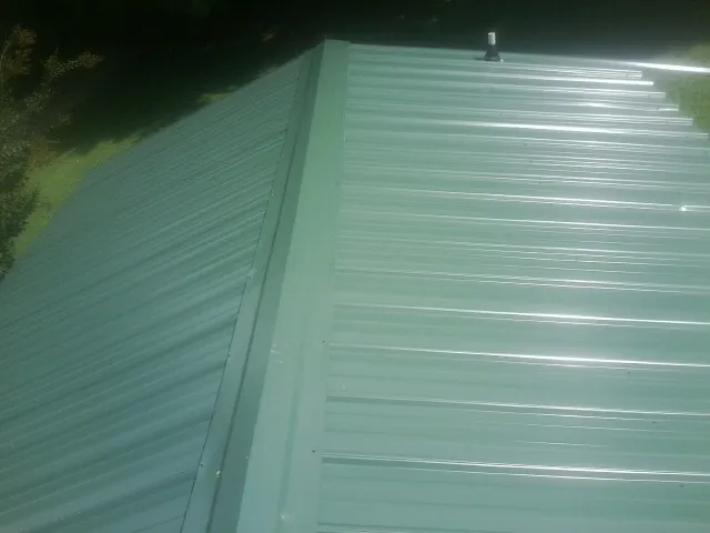 New green metal panels meeting at the ridge of a roof — Flat Roof Repair work by our crew in Lake Dallas