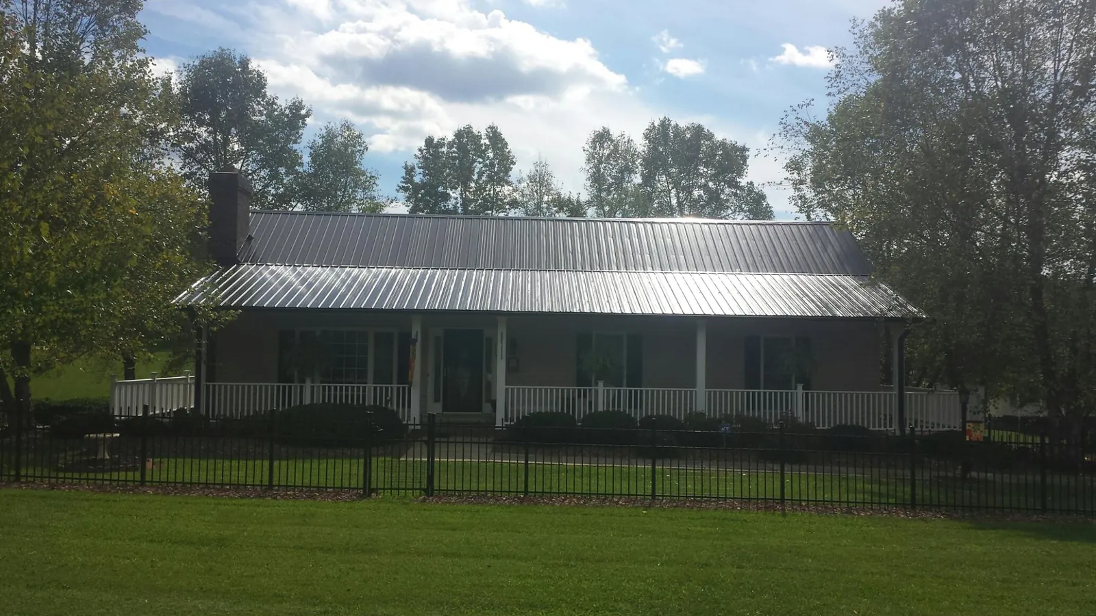 Gray metal roof on a brick ranch with a full width front porch — Gutter Guard Installation work by our crew in Lake Dallas
