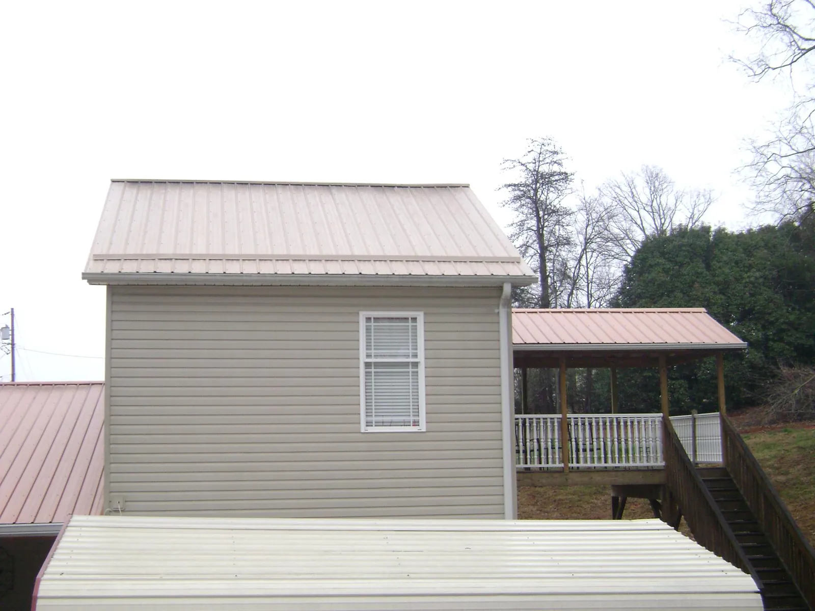 Tan metal roofs on a two story addition and attached porch, from a Roof Replacement job in Lake Dallas