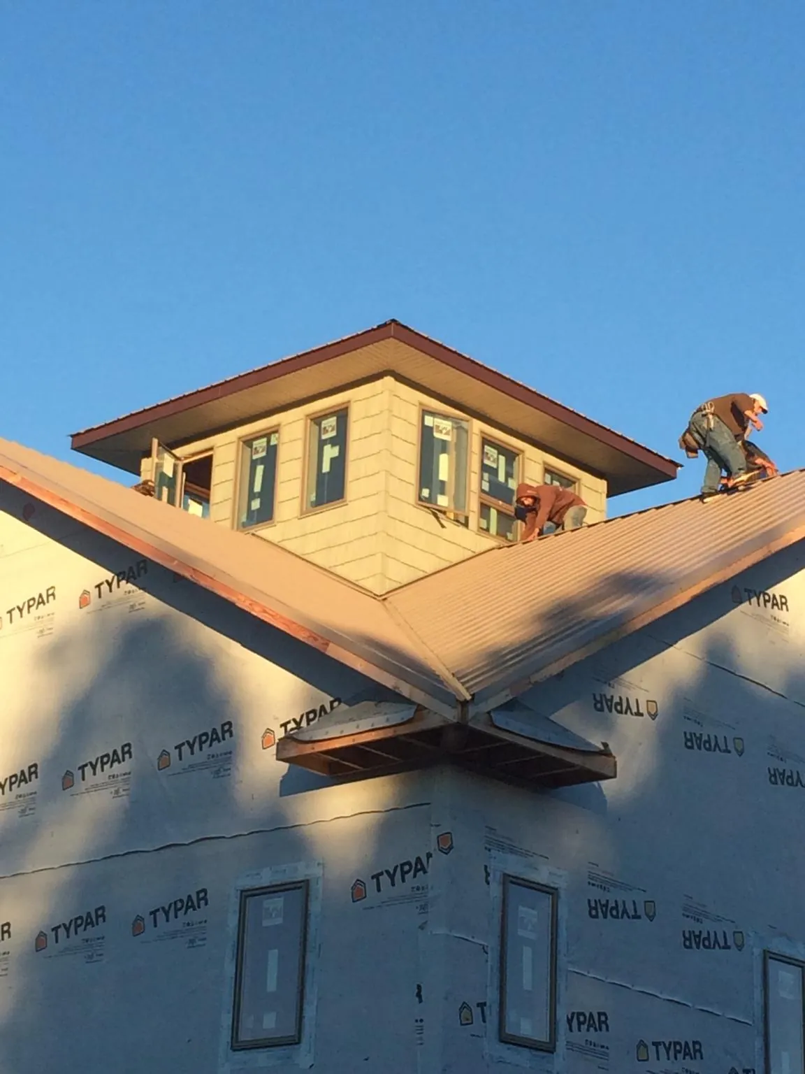 Roofers working around a rooftop cupola on a new metal roof at sunset — Roof Waterproofing in Lake Dallas by Roofing Brothers
